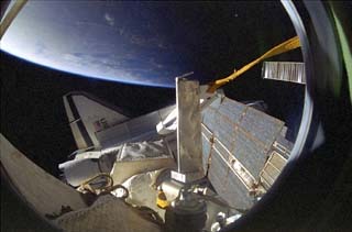 View of the shuttle port wing and payload bay door as seen from the Mir space station Base Block module. A Mir solar array can be seen just above the orbiter. 